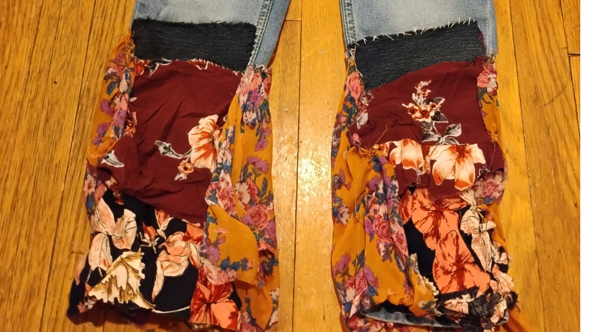 The image shows a pair of old jeans which were upcycled with repurposed blouse fabric.