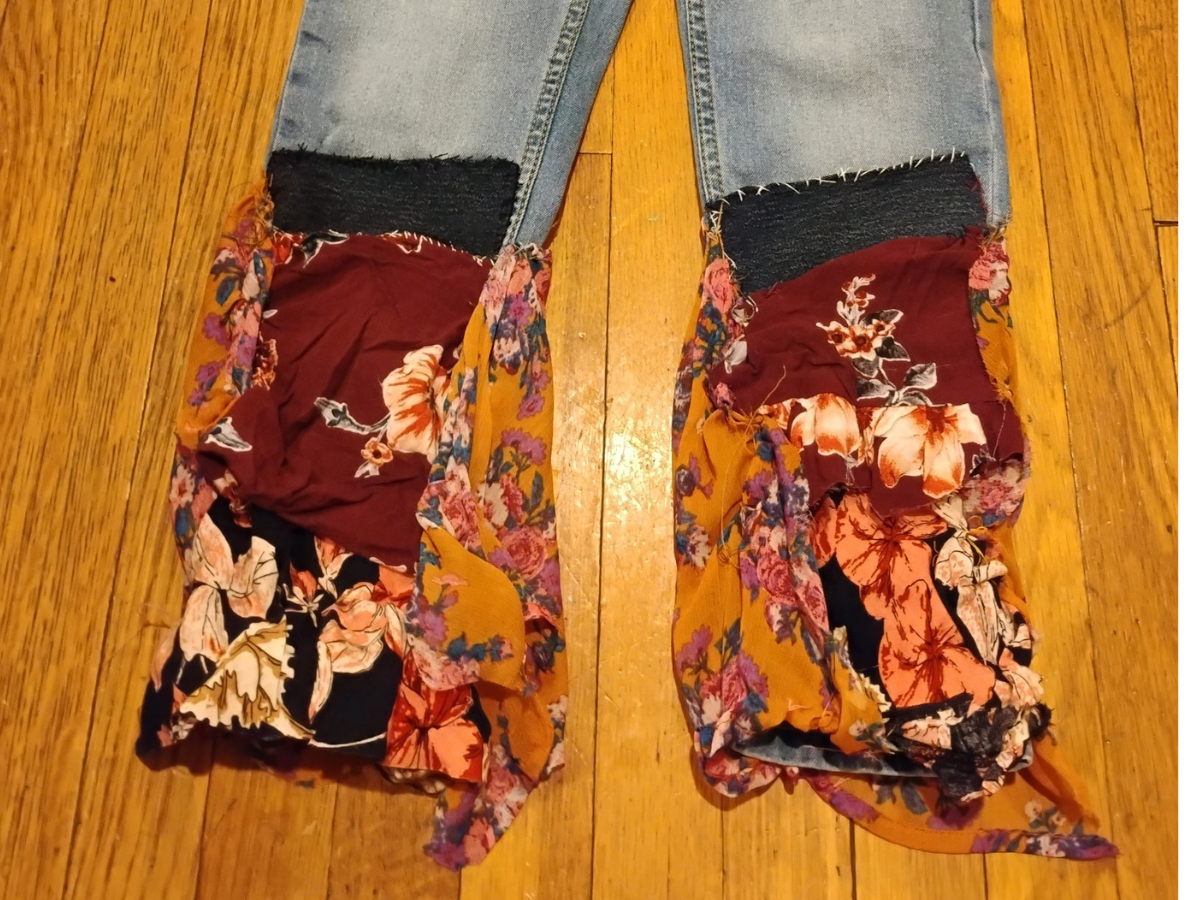The image shows a pair of old jeans which were upcycled with repurposed blouse fabric.